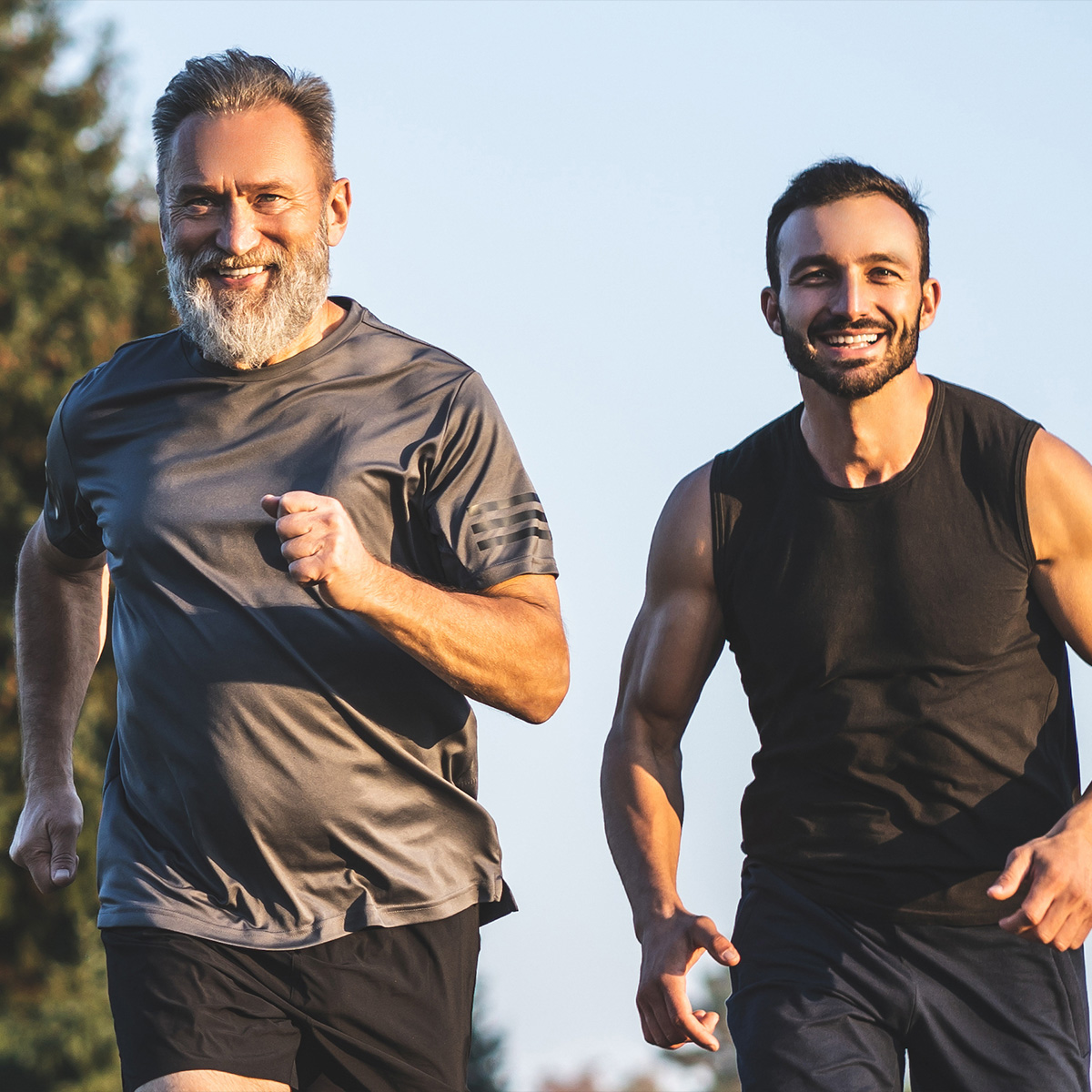 Older man and younger man running through a park.